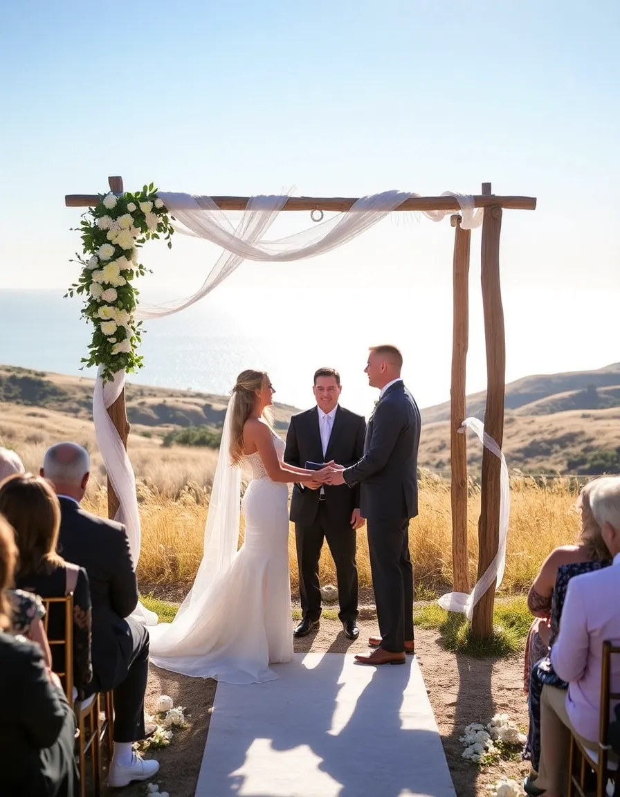 A wooden arch draped in white fabric and flowers at Calamigos Ranch, with a couple exchanging vows in front of a small gathering. The Pacific Ocean glimmers in the background, and the hills are covered in golden grasses swaying in the breeze.